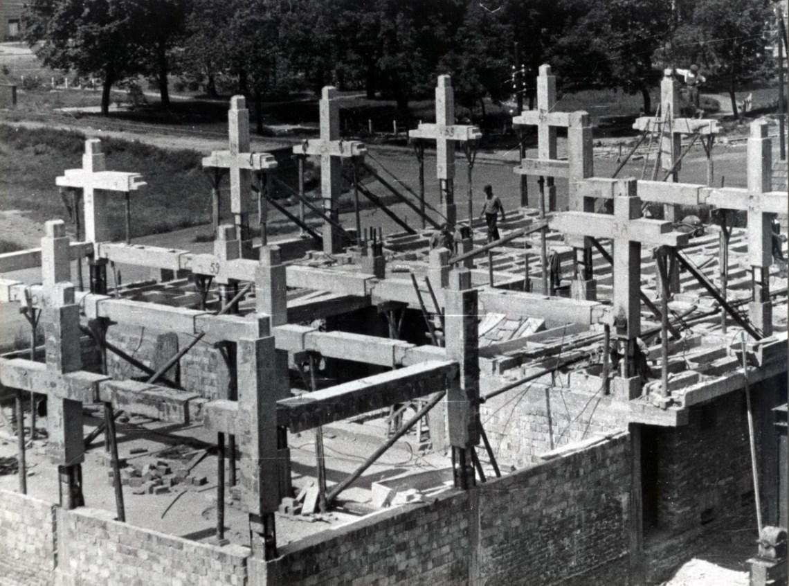 Az épület szerkezetének építése. Jól kivehetőek a kereszt alakú fő tartóelemek. Egymáshoz való csatlakozásuk oszlopközépnél és a gerendák nyomatéki nullpontjánál történt. (fotó: GYŐRITERV-es kiadvány)